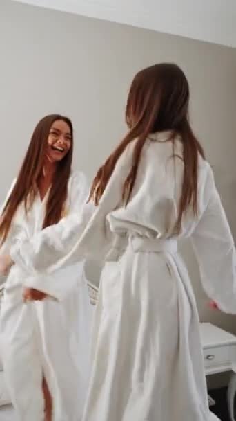 Dvě Mladé Ženy Županech Tančí Posteli Natáčejí Hotelová Dovolená Svislé — Stock video