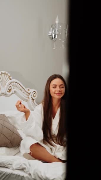 バスローブにいる2人の若い女性は 午前中にベッドで瞑想します 編集とヨガのコンセプト 垂直ビデオ — ストック動画