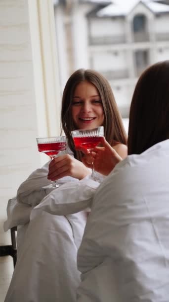 Две Молодые Женщины Одеялах Пьют Красные Коктейли Веселятся Балконе Видом — стоковое видео