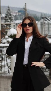 Terasta poz veren siyah takım elbiseli bir iş kadını. İş konsepti. Dikey video 4k