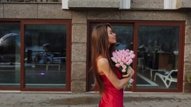 一个穿着红色衣服 山里有新鲜郁金香的漂亮女人的画像 这个女人拿着一束鲜花摆姿势向摄像机 — 图库视频影像