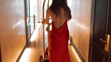 Kırmızı elbiseli iki seksi kadın bir otelde altın bir valiz vagonuna biniyor. Moda çekim konsepti