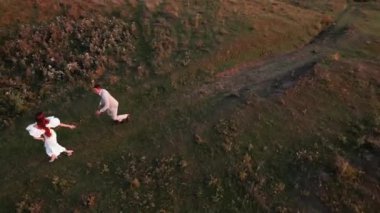 Gelin ve damat gün batımında güzel bir yerde yürüyorlar. Düğün gününden. Düğün konsepti. Bir İHA 4K çerçevesi