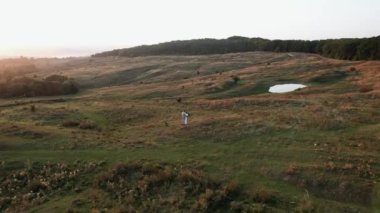 Gelin ve damat gün batımında güzel bir yerde yürüyorlar. Düğün gününden. Düğün konsepti. Bir İHA 4K çerçevesi