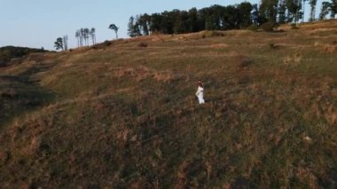 Gelin ve damat gün batımında güzel bir yerde yürüyorlar. Düğün gününden. Düğün konsepti. Bir İHA 4K çerçevesi