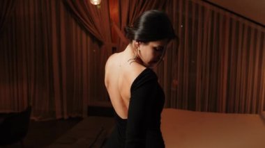 Siyah elbiseli zarif bir kadın. Siyah elbiseli ve kırmızı dudaklı bir kadın. Kameraya poz veriyor.