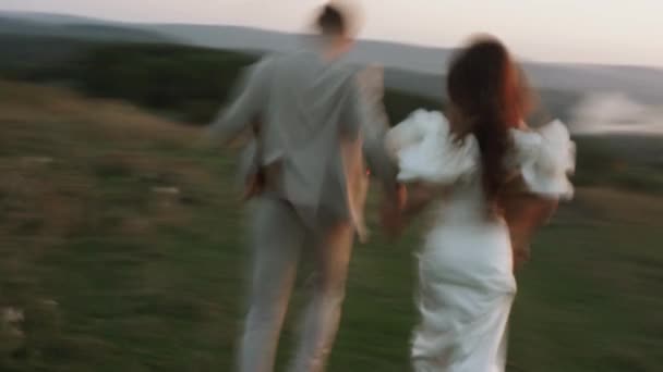 花嫁と新郎は美しい畑や丘を通って日没を歩き 笑ったり踊ったりします 結婚式の日のコンセプト — ストック動画