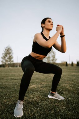 Spor giyim sektöründe genç bir kadın gün batımında spor egzersizleri yapıyor. Sağlıklı yaşam tarzı kavramı. Spor ve spor