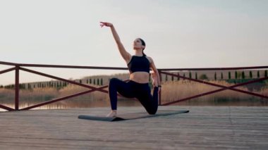 Genç kadın meditasyon yapıyor ve gün batımında göl kenarında yoga egzersizleri yapıyor. Yoga ve zindelik kavramı. Yoga asanas.