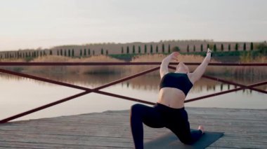Genç kadın meditasyon yapıyor ve gün batımında göl kenarında yoga egzersizleri yapıyor. Yoga ve zindelik kavramı. Yoga asanas.