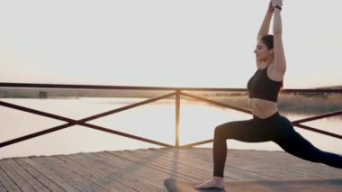 Genç kadın meditasyon yapıyor ve gün batımında göl kenarında yoga egzersizleri yapıyor. Yoga ve zindelik kavramı. Yoga asanas.