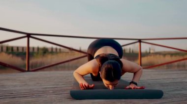 Genç kadın meditasyon yapıyor ve gün batımında göl kenarında yoga egzersizleri yapıyor. Yoga ve zindelik kavramı. Yoga asanas.