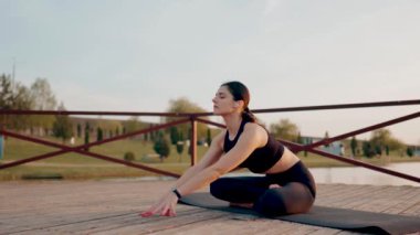 Genç kadın meditasyon yapıyor ve gün batımında göl kenarında yoga egzersizleri yapıyor. Yoga ve zindelik kavramı. Yoga asanas.