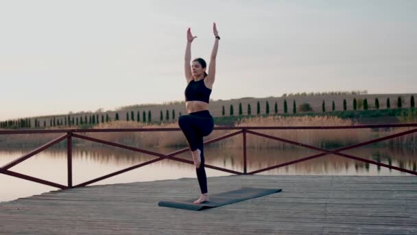 年轻女子在日落时在湖堤上冥想和做瑜伽练习 瑜伽和健身的概念 — 图库视频影像