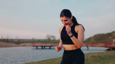 Spor giyimli genç bir kadın gün batımında setin yanında koşuyor. Sağlıklı yaşam tarzı kavramı