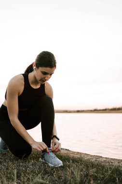 Spor giyimli genç bir kadın gün batımında setin yanında koşuyor. Sağlıklı yaşam tarzı kavramı