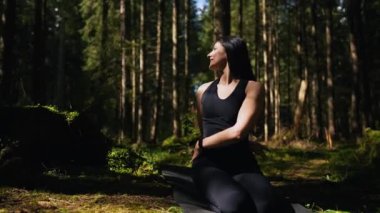 Genç bir kadın ormanda yoga yapıyor ve meditasyon yapıyor. Yoga ve meditasyon konsepti. Yoga asanası. 4K