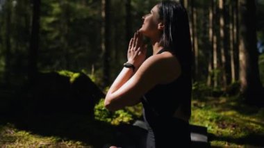 Genç bir kadın ormanda yoga yapıyor ve meditasyon yapıyor. Yoga ve meditasyon konsepti. Yoga asanası. 4K