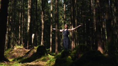Genç bir kadın ormanda yoga yapıyor ve meditasyon yapıyor. Yoga ve meditasyon konsepti. Yoga asanası. 4K