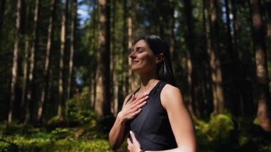 Genç bir kadın ormanda yoga yapıyor ve meditasyon yapıyor. Yoga ve meditasyon konsepti. Yoga asanası. 4K