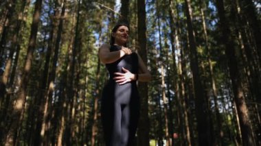 Genç bir kadın ormanda yoga yapıyor ve meditasyon yapıyor. Yoga ve meditasyon konsepti. Yoga asanası. 4K