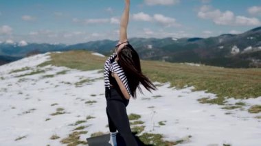 Karlı dağların tepesinde meditasyon yapan genç bir kadın. Yoga ve meditasyon konsepti. Yoga asanas 4k.