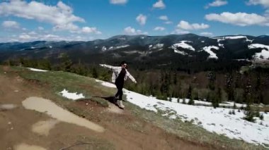 Mutlu bir kadın kar kaplı dağların tepesinde koşar ve dans eder. Seyahat konsepti. 4k İHA atışı