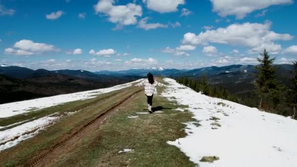 幸せな女性が雪に覆われた山の頂上に走ったり踊ったりします 旅行コンセプト 4Kドローンショット — ストック動画