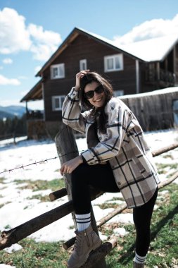 Karla kaplı dağların arkasında poz veren genç bir kadın. Dağlarda tatil kavramı..