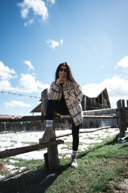 Karla kaplı dağların arkasında poz veren genç bir kadın. Dağlarda tatil kavramı..