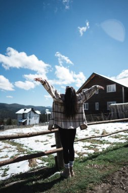 Karla kaplı dağların arkasında poz veren genç bir kadın. Dağlarda tatil kavramı..