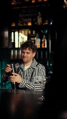 Karizmatik bir barmen bir kadın için alkollü kokteyl yapar. Kulüp eğlence konsepti. Dikey video