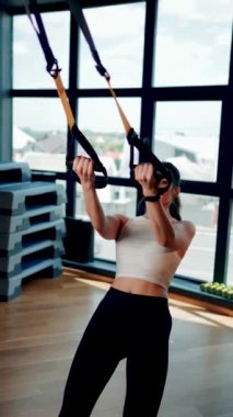 Trx Sistemle egzersiz yapan güzel bir kadın. Döngülerle spor yapıyor. Sağlıklı yaşam tarzı sporu hariç.