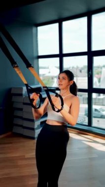Trx Sistemle egzersiz yapan güzel bir kadın. Döngülerle spor yapıyor. Sağlıklı yaşam tarzı sporu hariç.