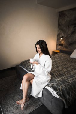 Genç bir kadın sabah otel odasında aromatik espresso kahvenin tadını çıkarıyor. Kahve konsepti.