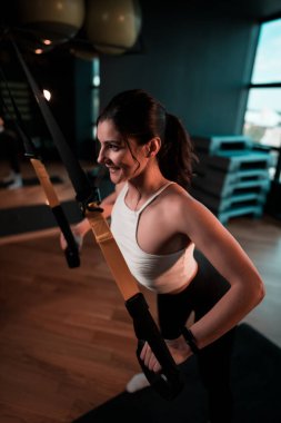 Trx Sistemle egzersiz yapan güzel bir kadın. Döngülerle spor yapıyor. Sağlıklı yaşam tarzı sporu kavramı..