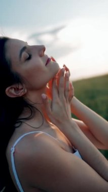 Beyaz elbiseli güzel bir kadın yeşil buğday tarlasında poz veriyor ve dans ediyor. Özgürlük kavramı. Dikey video