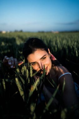 Beyaz elbiseli güzel bir kadın yeşil buğday tarlasında poz veriyor ve dans ediyor. Özgürlük kavramı. Yeşil buğday tarlasında fotoğraf çekimi.