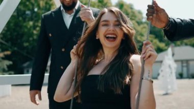 Bir grup yetişkin çocuk gibi çocuk parkında oynayıp gülüyor. Yetişkinler çocuk salıncağında oynuyor. Çocukluk nostaljisi kavramı.