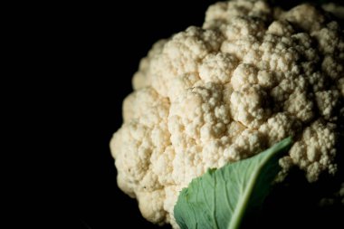 Raw cauliflower in a plate on a black background.Vegetables concept clipart