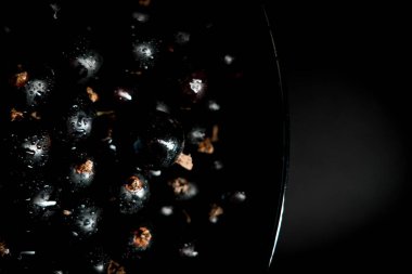 Siyah arka planda siyah bir tabakta frenk üzümü. Böğürtlen kavramı