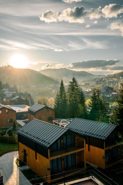 Resimli kahverengi evler karla kaplı dağların arka planına karşı. Dağlardaki yaşam konsepti. Dağlardaki evler