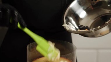 Bir kadın pasta şefi mango tutkulu meyveli pasta hazırlıyor. Pasta şefi pastaya krema sürüyor. Pasta şefi pastanın katmanlarını topluyor..