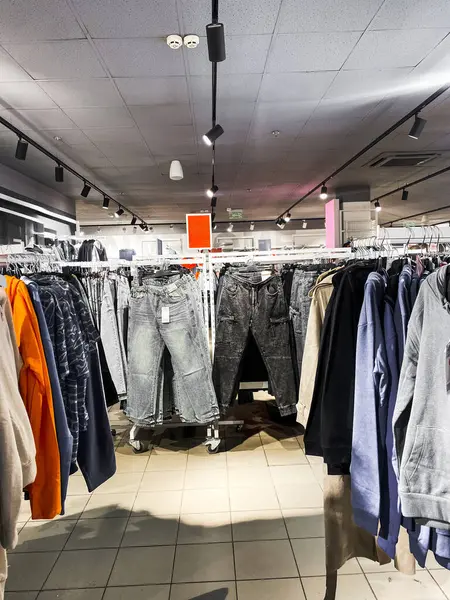 Kıyafet mağazasının genel manzarası. Giysileri, pantolonları, ayakkabıları ve şapkaları olan raflar. Alışveriş konsepti