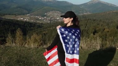 Genç bir kadın bir Amerikan bayrağını dağın tepesinde tutuyor. Amerikan bayrağı taşıyan bir kadın. Özgürlük ve demokrasi kavramı. ABD 'de seçimler
