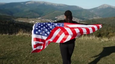 Genç bir kadın bir Amerikan bayrağını dağın tepesinde tutuyor. Amerikan bayrağı taşıyan bir kadın. Özgürlük ve demokrasi kavramı. ABD 'de seçimler