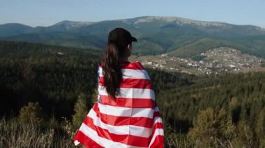 Genç bir kadın bir Amerikan bayrağını dağın tepesinde tutuyor. Amerikan bayrağı taşıyan bir kadın. Özgürlük ve demokrasi kavramı. ABD 'de seçimler