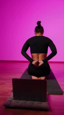 Bilgisayarla yoga yapan genç bir kadın..