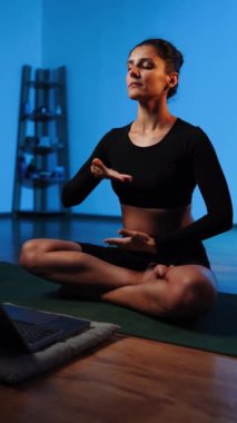 Bilgisayarla yoga yapan genç bir kadın..