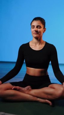 Bilgisayarla yoga yapan genç bir kadın..